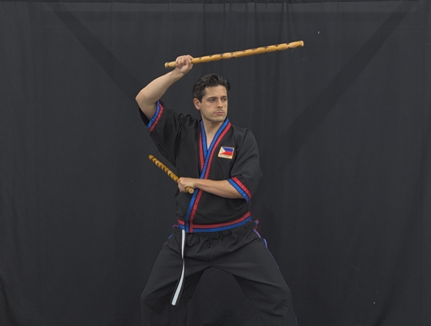 Modern Arnis Mano-Mano instructor with double rattan sticks in overhead strike