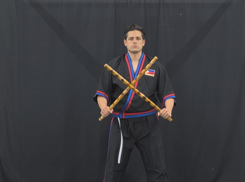 Modern Arnis Mano-Mano instructor with crossed rattan sticks