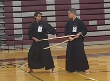 Instructor performing Seitei Jodo kata with sensei holding the bokuto